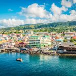 A panoramic view of Roseau, Dominica, showcasing colorful buildings along the Caribbean coastline under a bright blue sky.