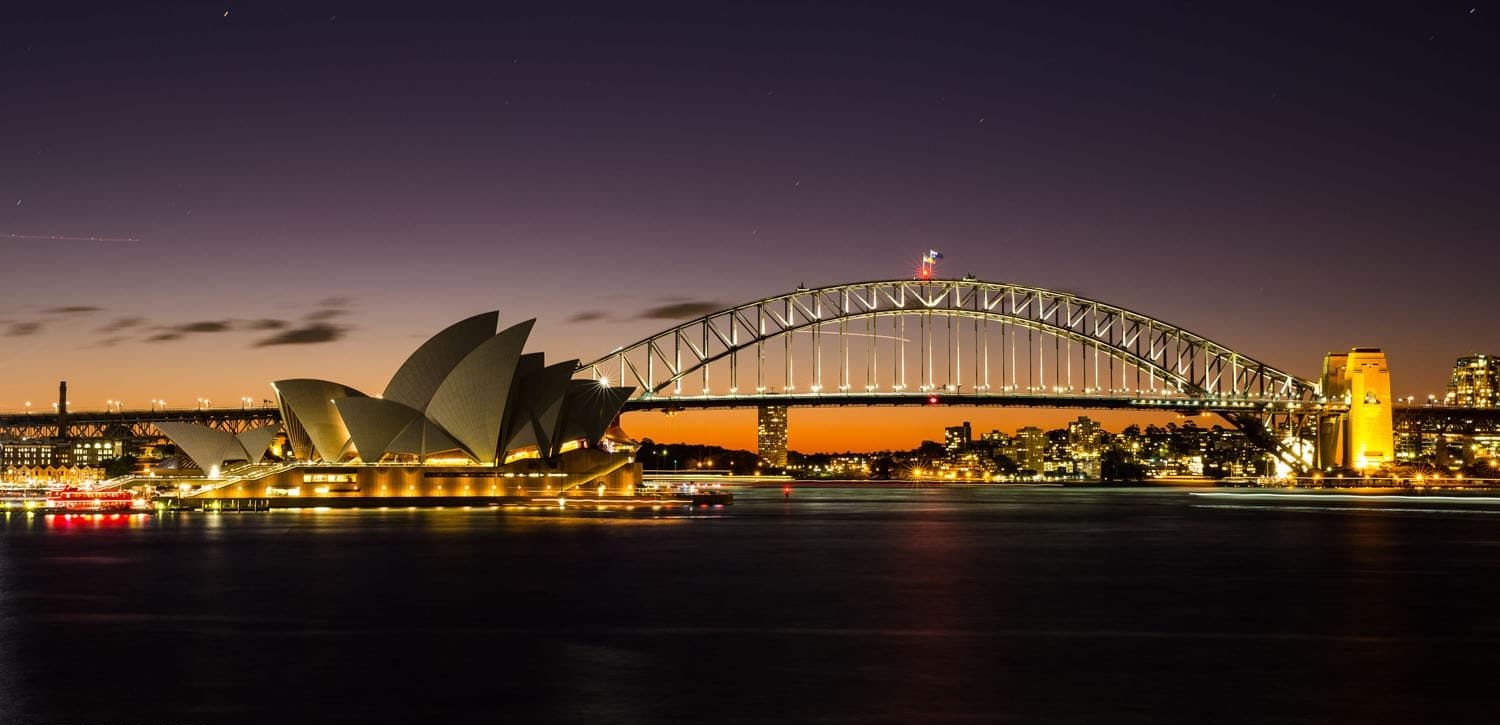 A panoramic view of Sydney Harbour featuring the Opera House and Harbour Bridge.