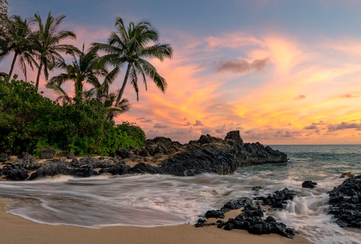 Tropical beach in Hawaii with palm trees and sunset sky