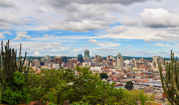 A panoramic view of Lusaka city with modern buildings and busy streets under a blue sky